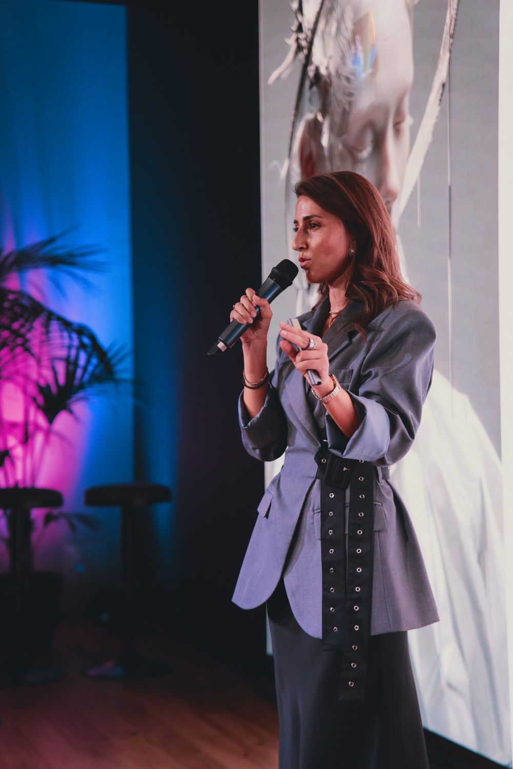 Camilla Brossa speaks into the microphone in front of a futuristic face projected on the screen, during her talk