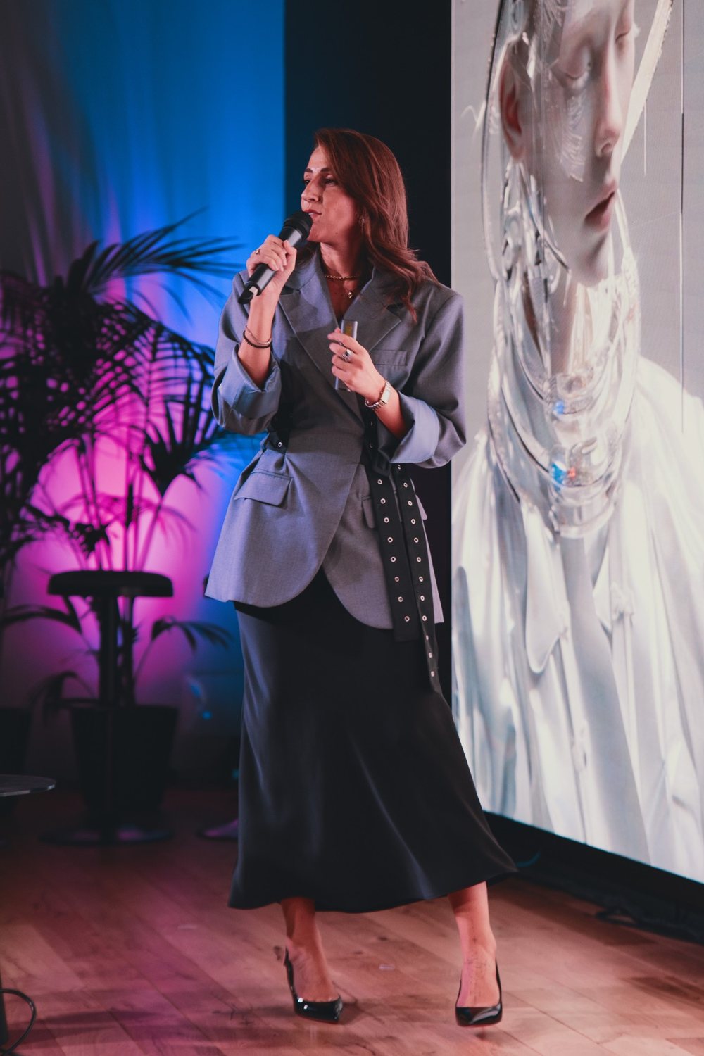 Camilla Brossa full-length on the Feat House stage in Turin, at the microphone between the blue curtain, palms and screen