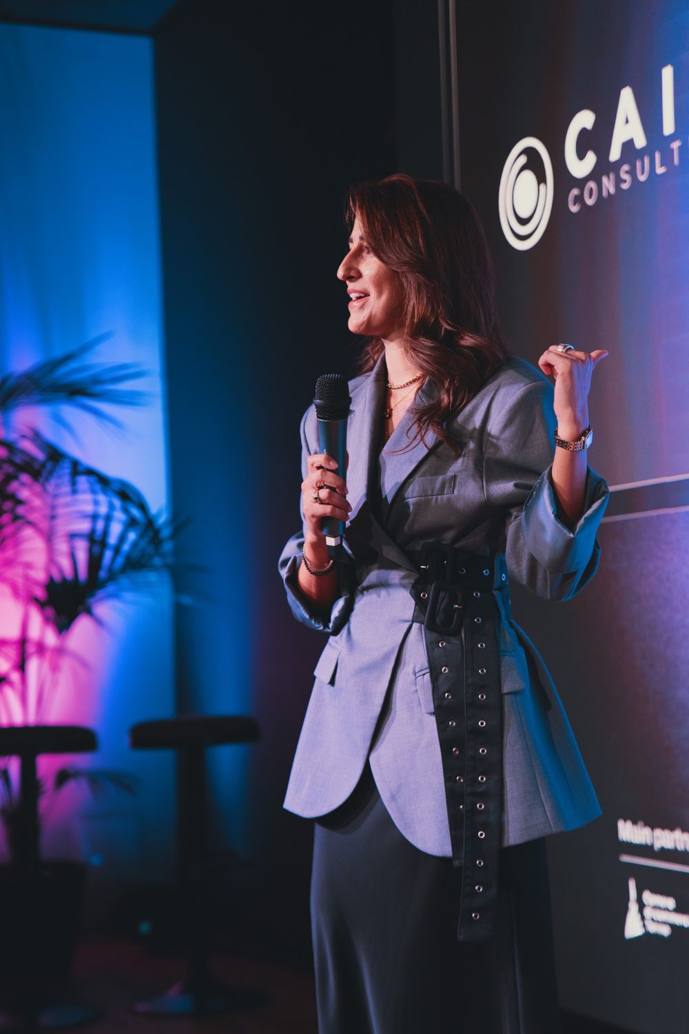 Camilla Brossa smiles and points to the screen showing the CAIA Consulting mark, her consulting firm